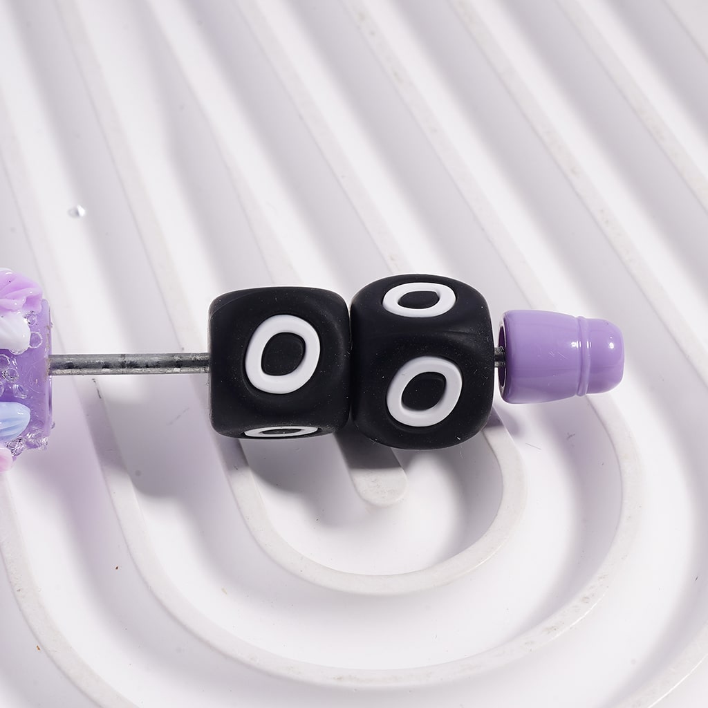 Black dice-shaped beads with white circles on a white background