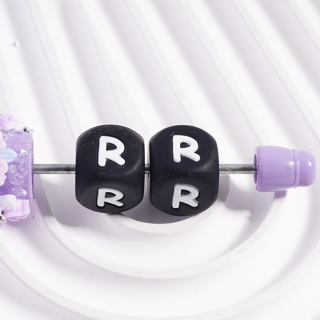 Black letter 'R' beads on a white background