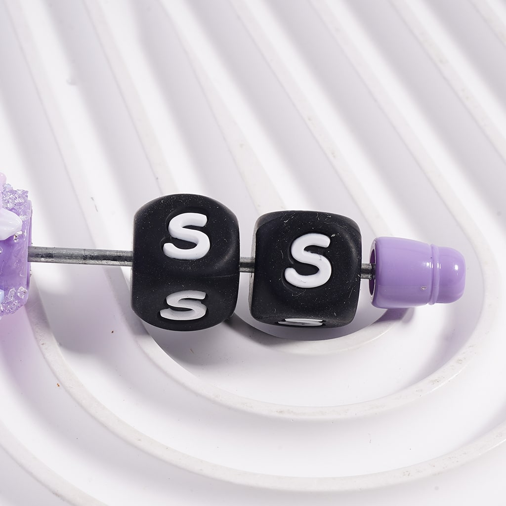 Close-up of earbud tips with 'S' markers and purple accents on a white background