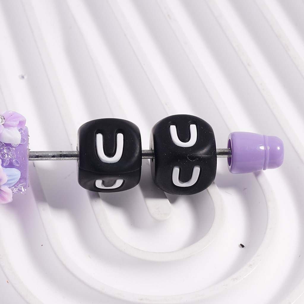 Black beads with 'U' letters on a white background