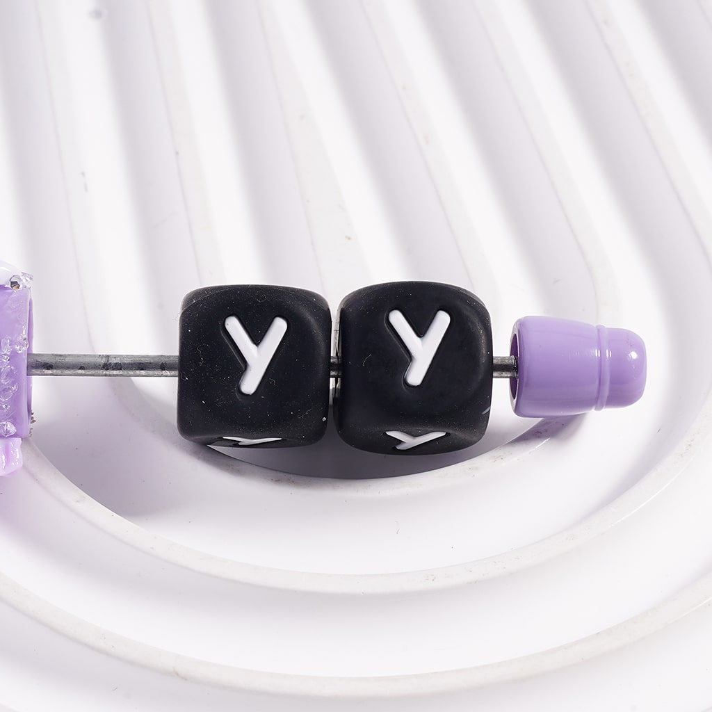Black letter 'Y' beads on a white background