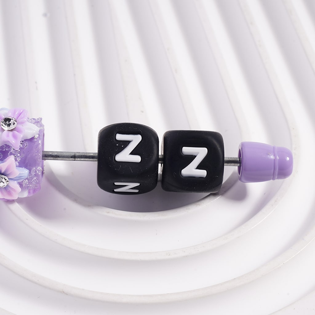 Black letter 'Z' beads with purple accents on a white background