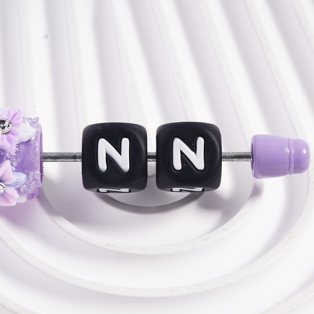 Necklace with black cube beads displaying 'NN' on a white background