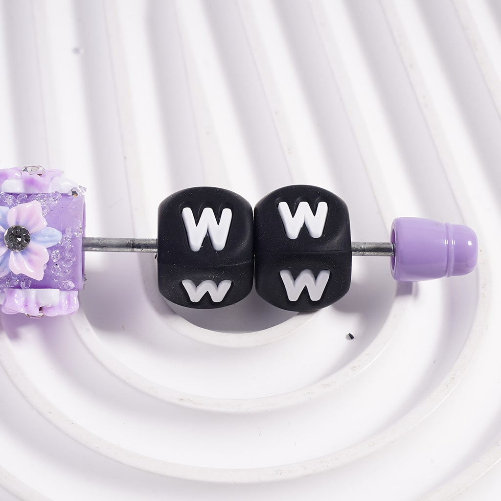 Beads with 'W' letters and purple floral design on a white background