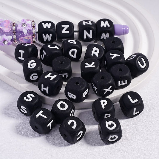 Black letter beads with white letters on a white background