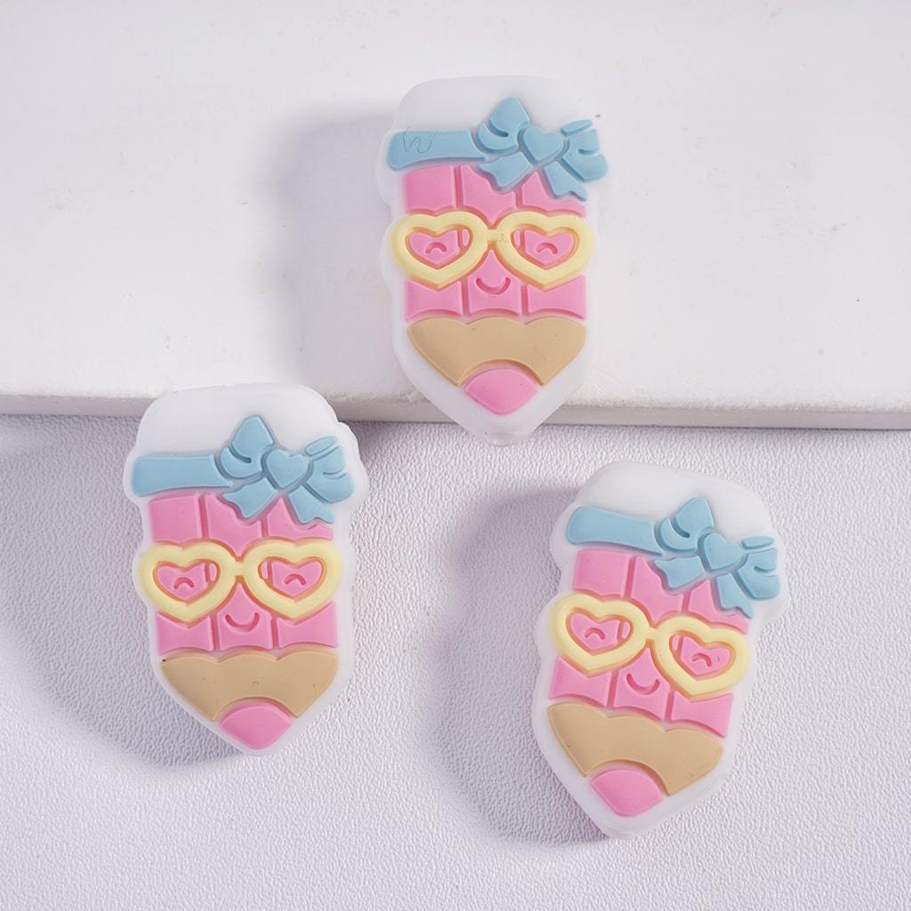 Three pastel-colored shoe-shaped charms with bows and heart designs on a white background