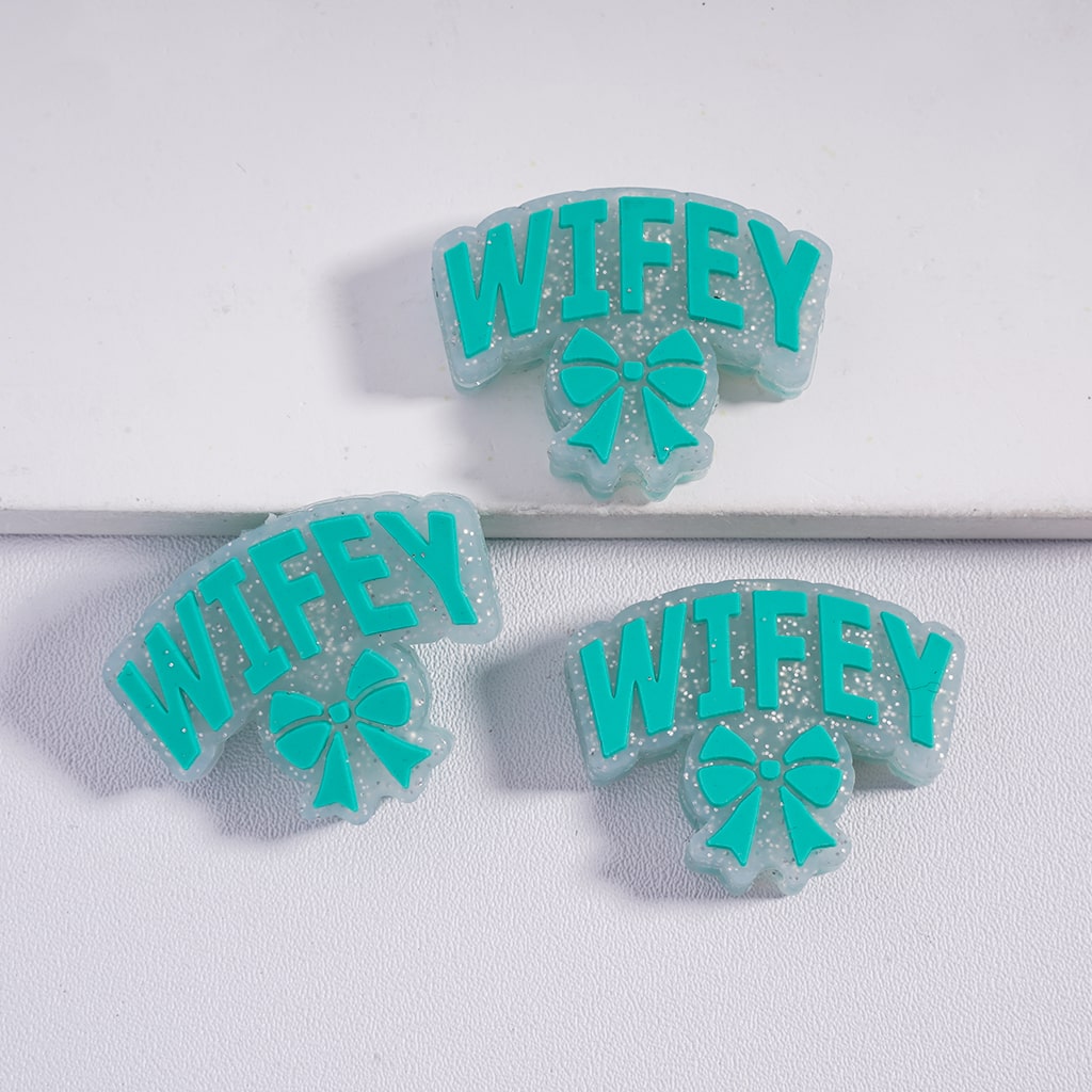 Three 'WIFEY' earrings with teal bows on a white background