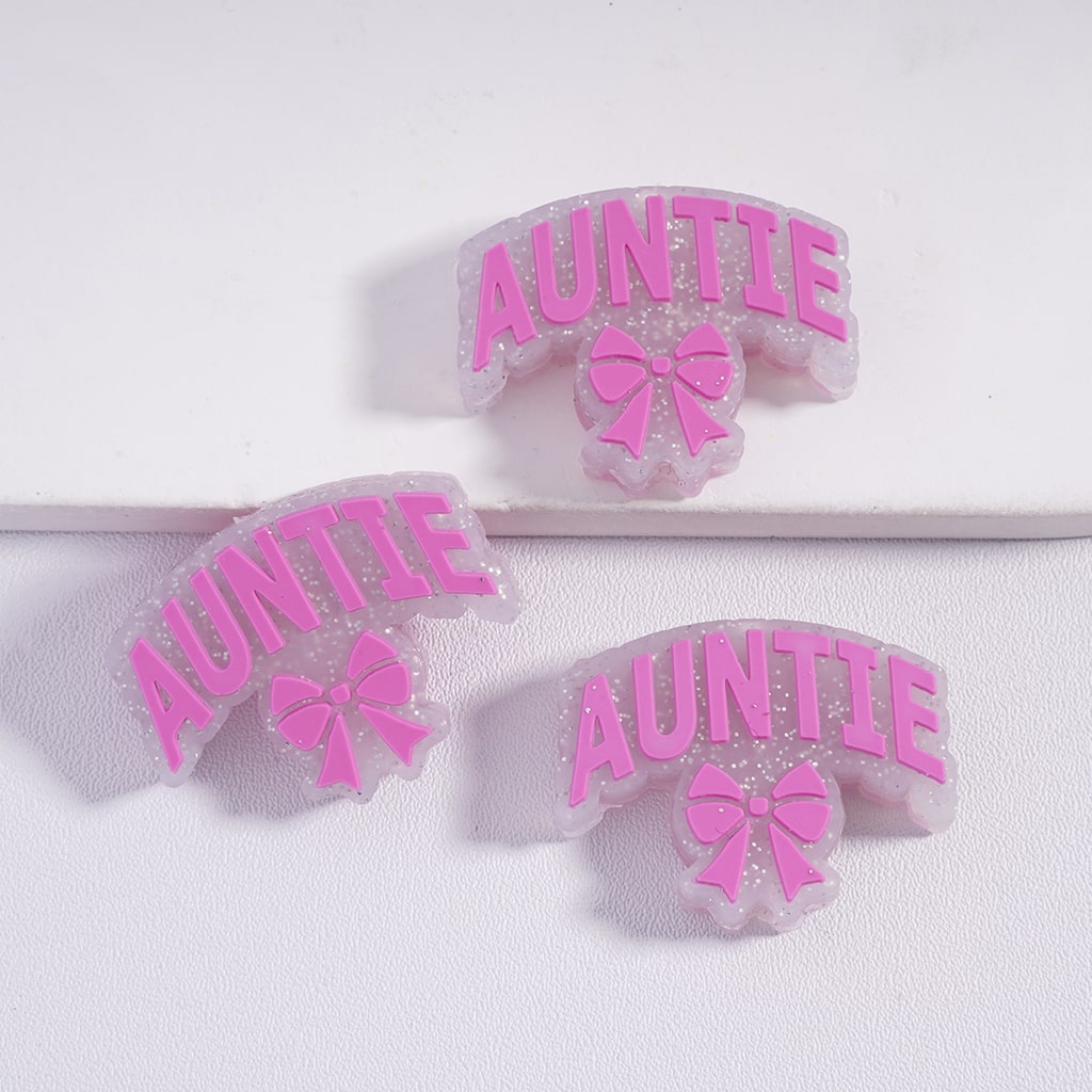 Three pink 'Auntie' hair ties with bows on a white background