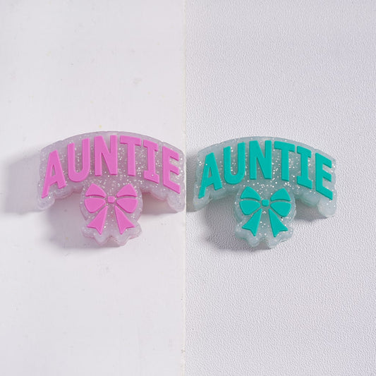 Two hair clips with 'AUNTIE' text and bow designs on a white background