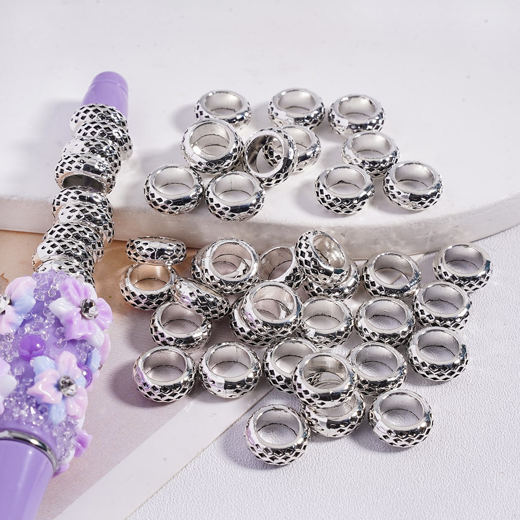 Silver beads and a purple hairbrush on a white background