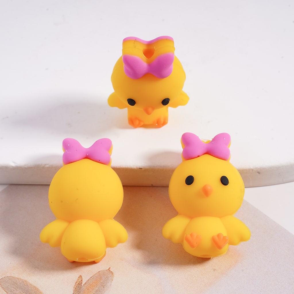 Three yellow rubber duck toys with pink bows on a light background