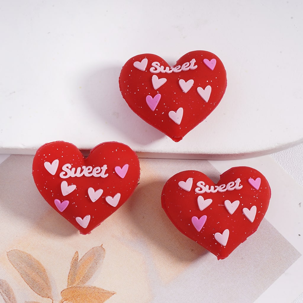 Red heart-shaped cookies with 'Sweet' and heart patterns on a white plate.