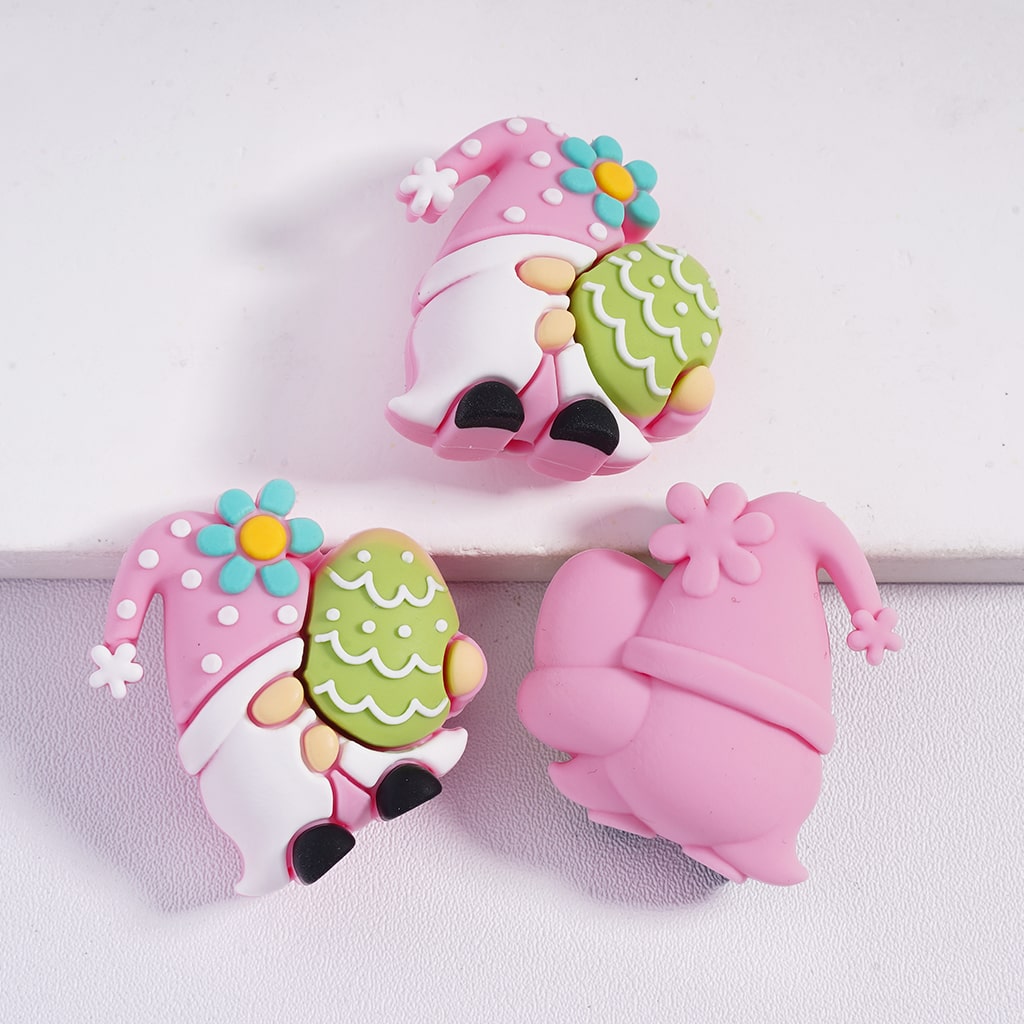 Two pink gnome-shaped items with green hats on a white background