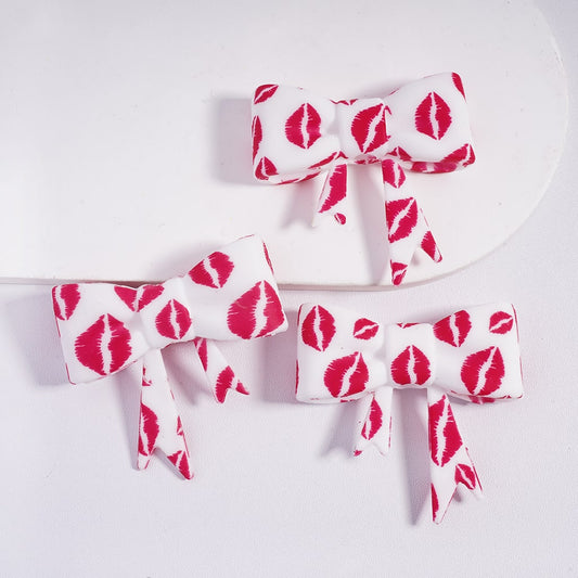 Three hair bows with red kiss mark pattern on a white background