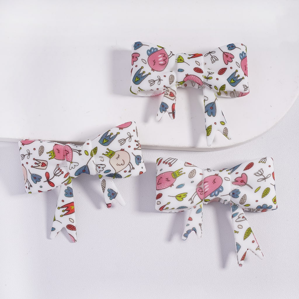 Set of three colorful bow-shaped hair accessories on a white background