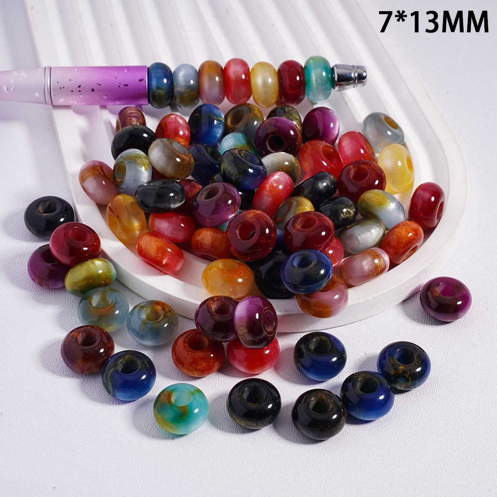 Assorted colored beads on a white surface with a measuring tool.
