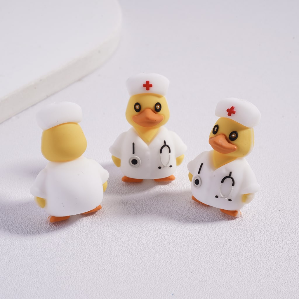 Three rubber duck toys dressed as a doctor and a nurse on a white background