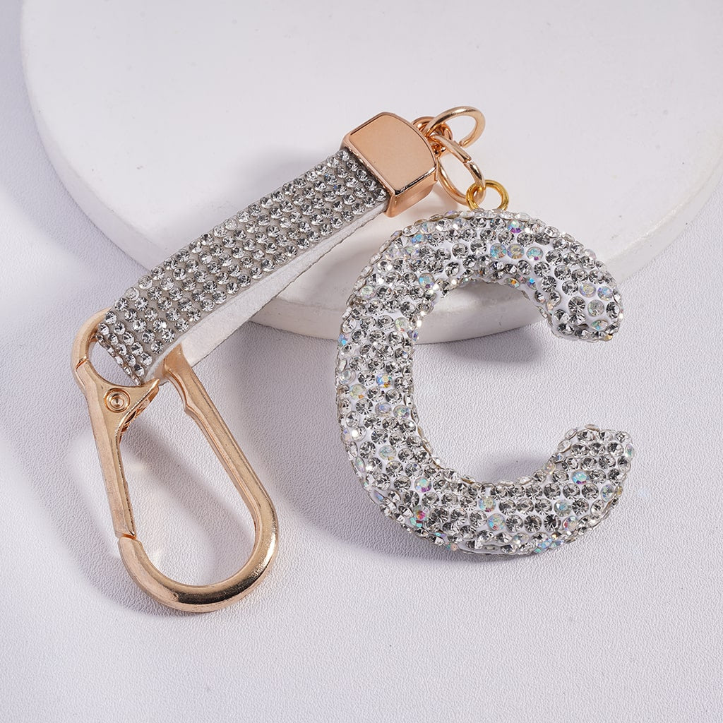 Keychain with gold carabiner and letter 'C' charm on a light gray background
