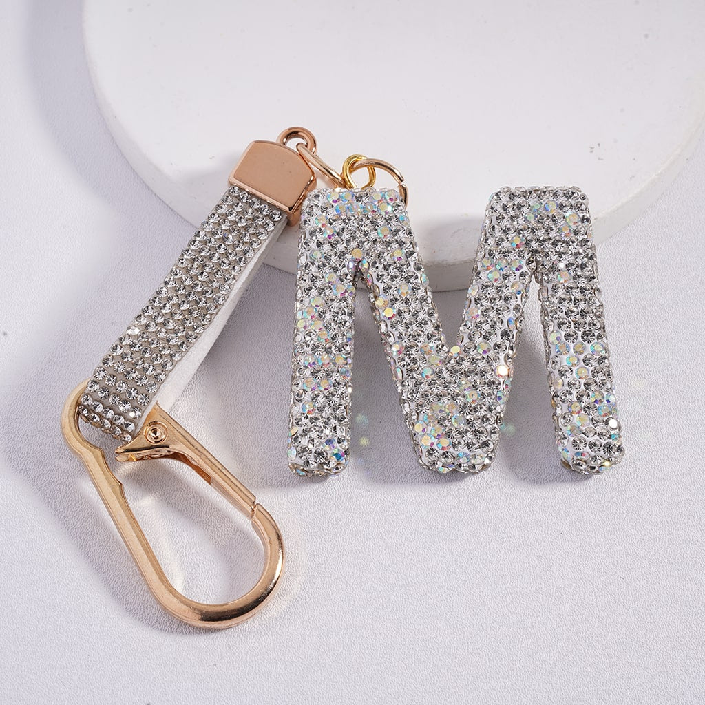 Sparkly letter 'M' keychain with gold carabiner on a light background