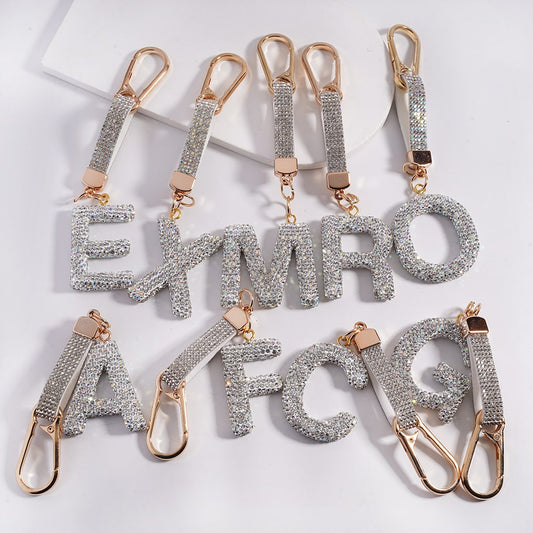 Silver letter keychains with gold accents on a white background