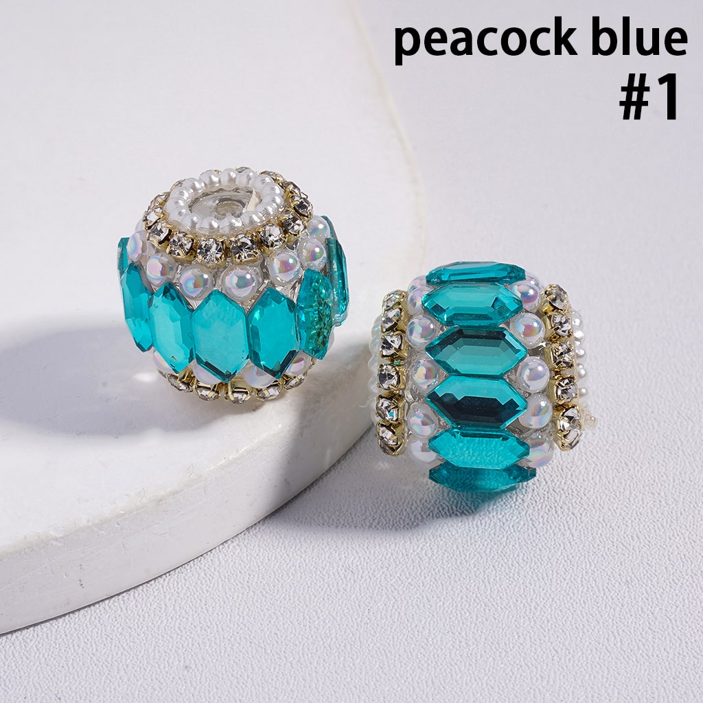 Two peacock blue jewelry beads with gold accents on a white background
