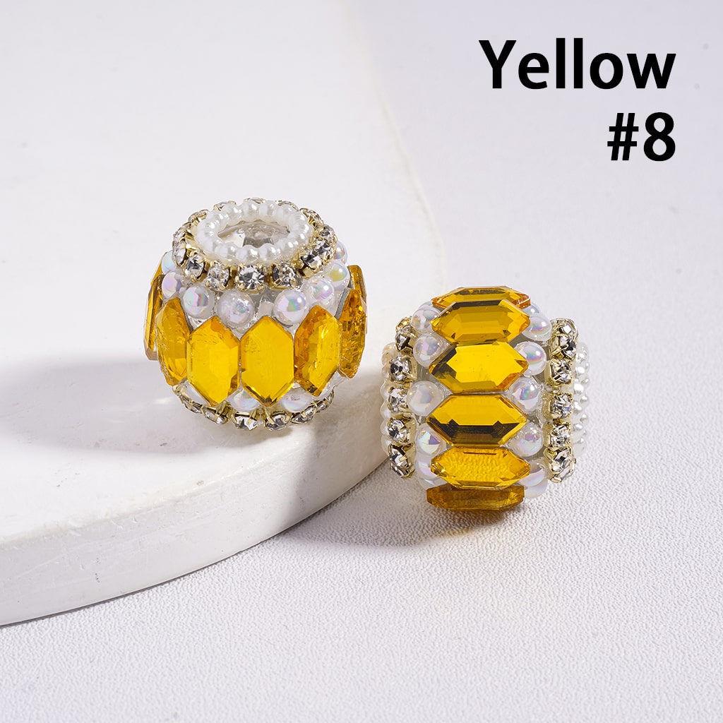 Two yellow jewelry beads with white accents on a light background