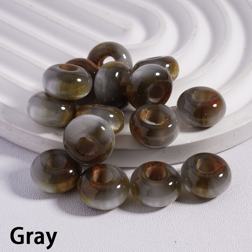 Gray beads on a textured white surface with a white circular object in the background.