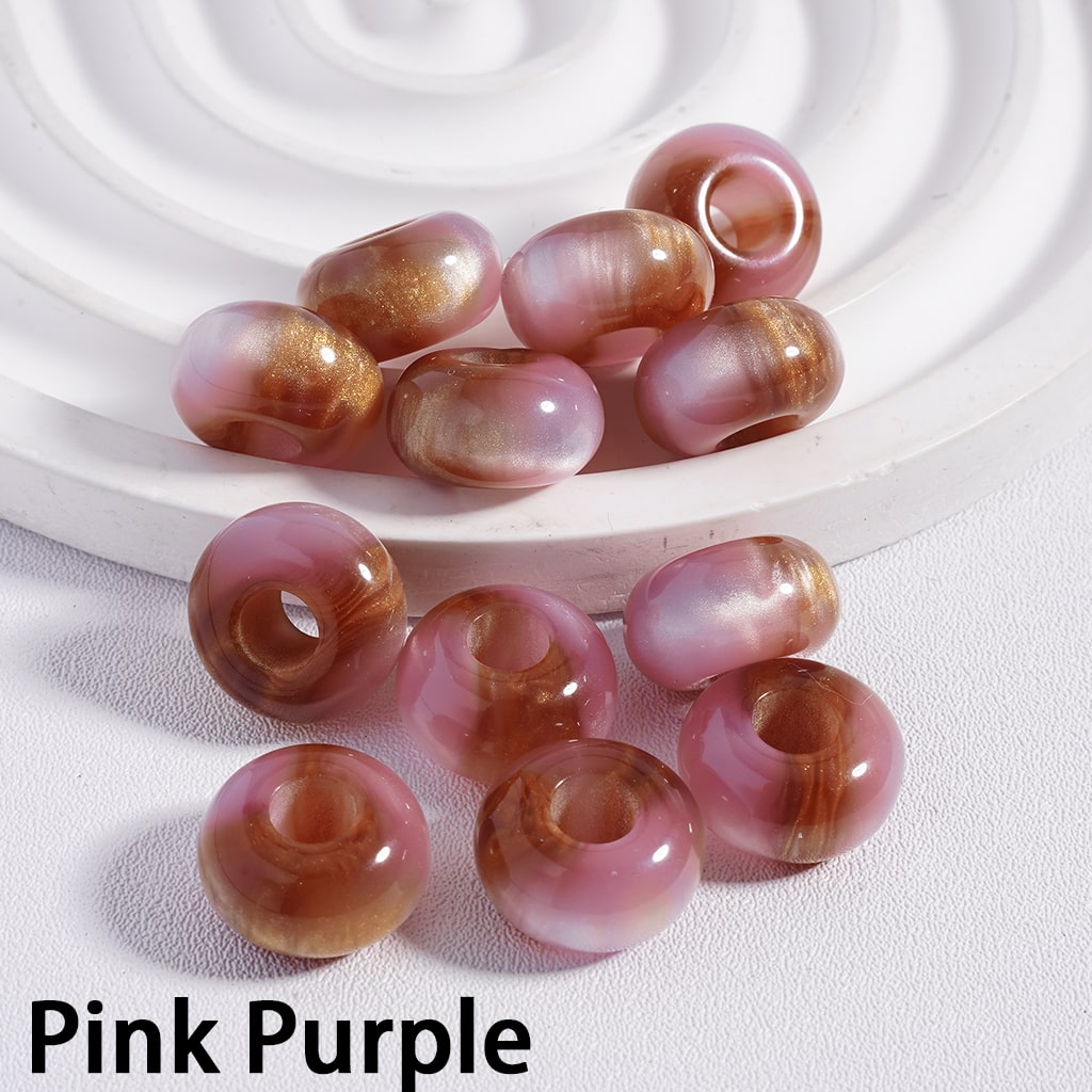 Pink and purple beads on a white surface with a white circular object in the background.