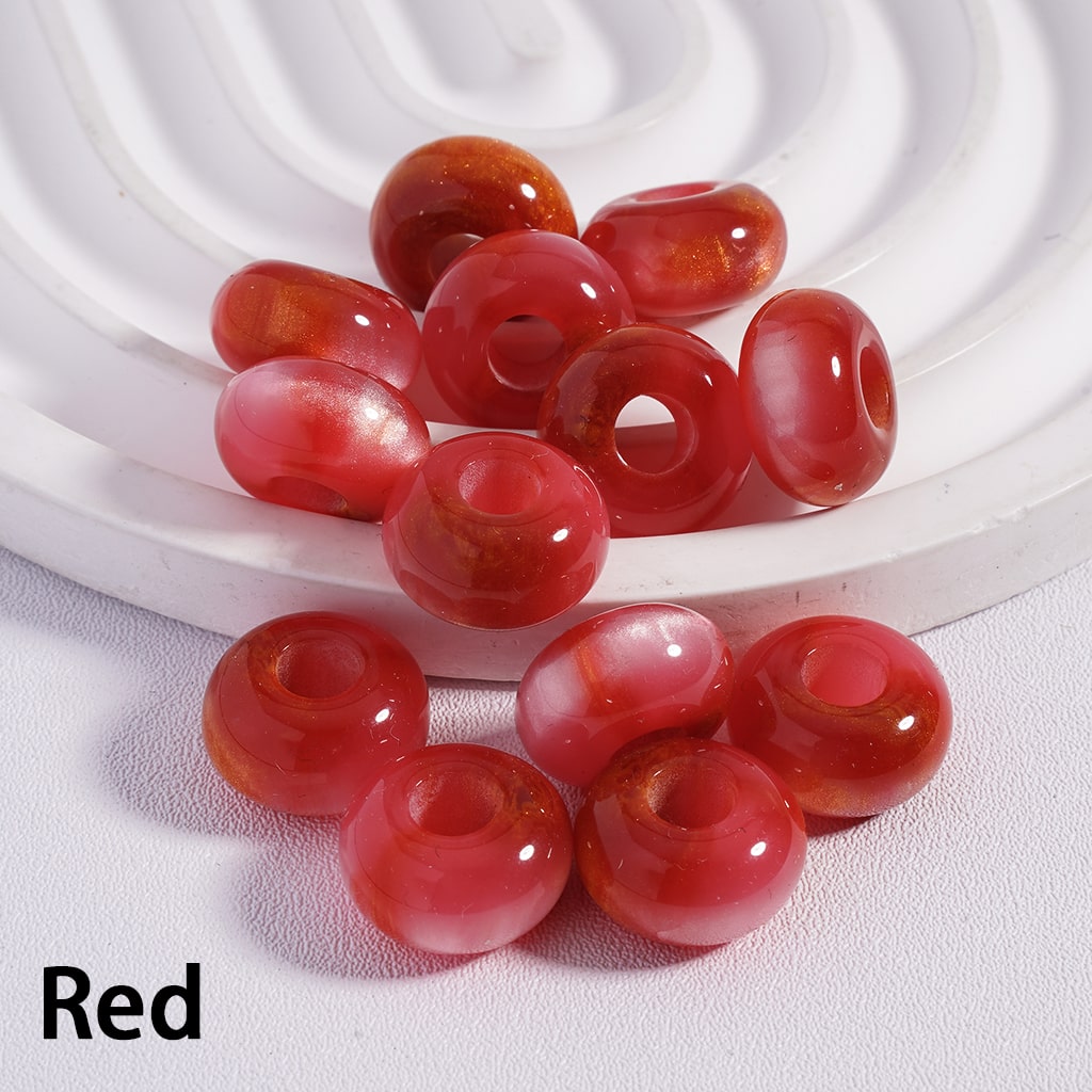 Red beads on a white textured surface with a white circular object in the background.