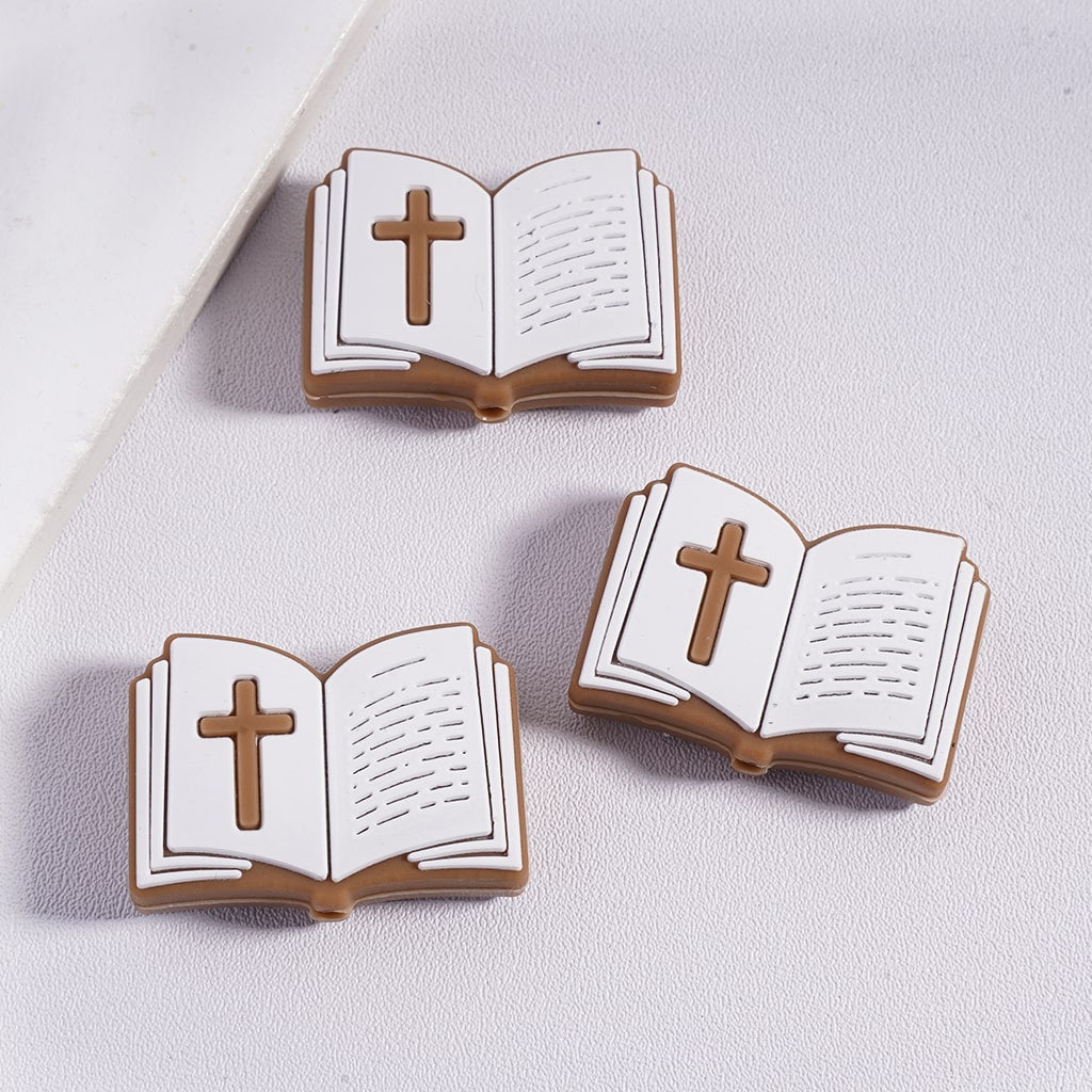 Three cookies shaped like open books with crosses on a light gray background