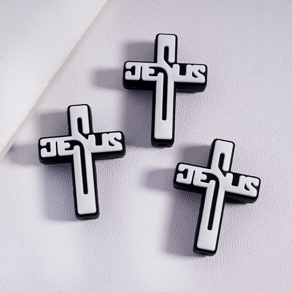 Three black and white cross-shaped 'Jesus' pins on a light gray background