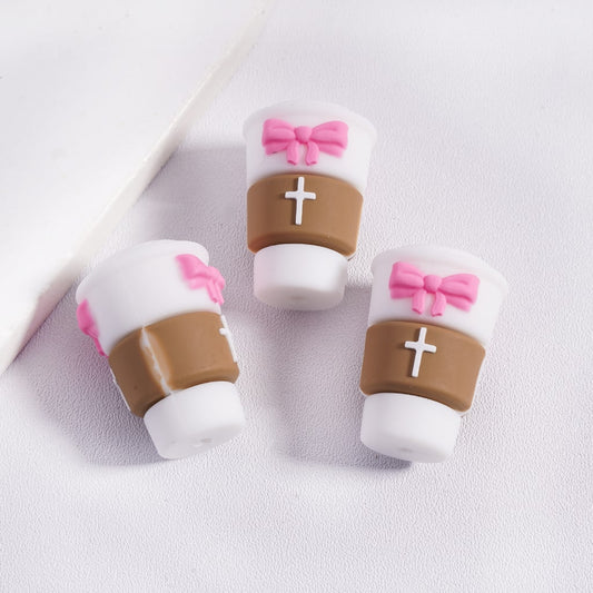 Three small cylindrical candies with pink bows and white crosses on a light gray background
