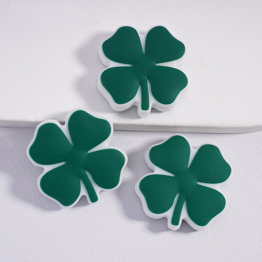 Three green four-leaf clover-shaped objects on a white background