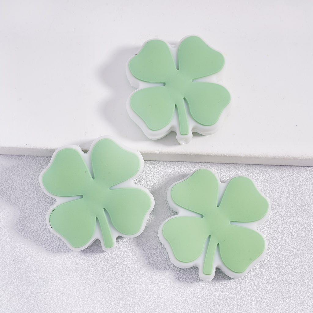 Three green four-leaf clover-shaped objects on a white background