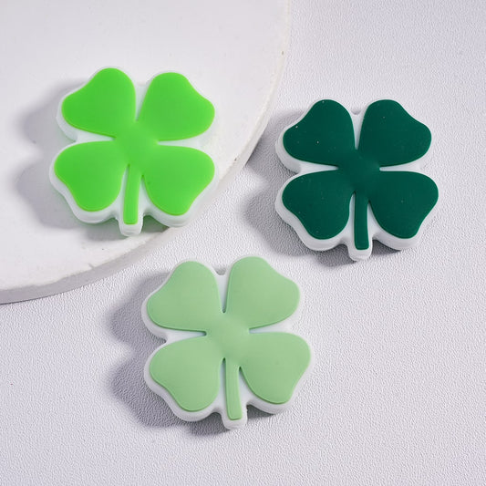 Three green four-leaf clover-shaped objects on a light gray background