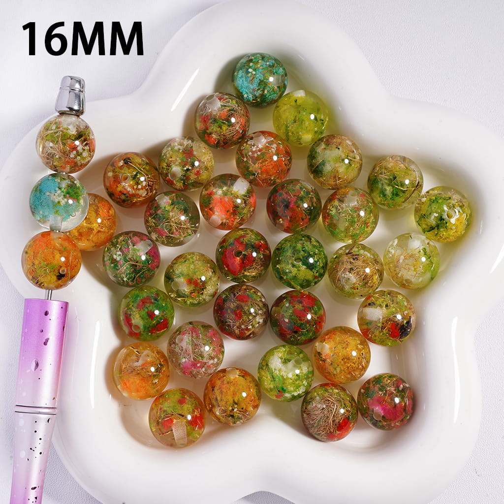 Colorful beads on a white heart-shaped dish with a pen next to them, labeled '16MM'.