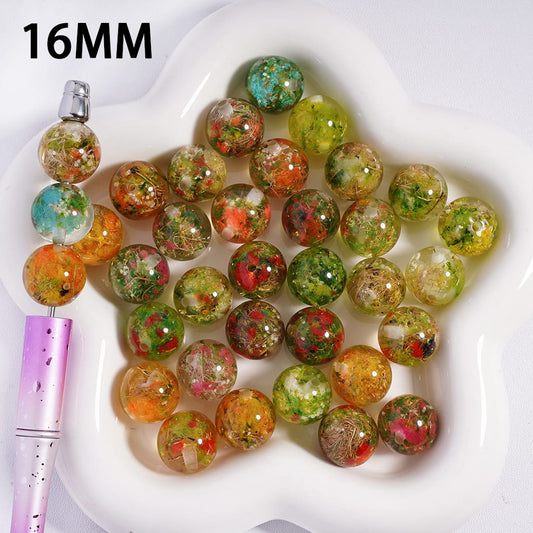 Colorful beads on a white heart-shaped dish with a pen next to them, labeled '16MM'.