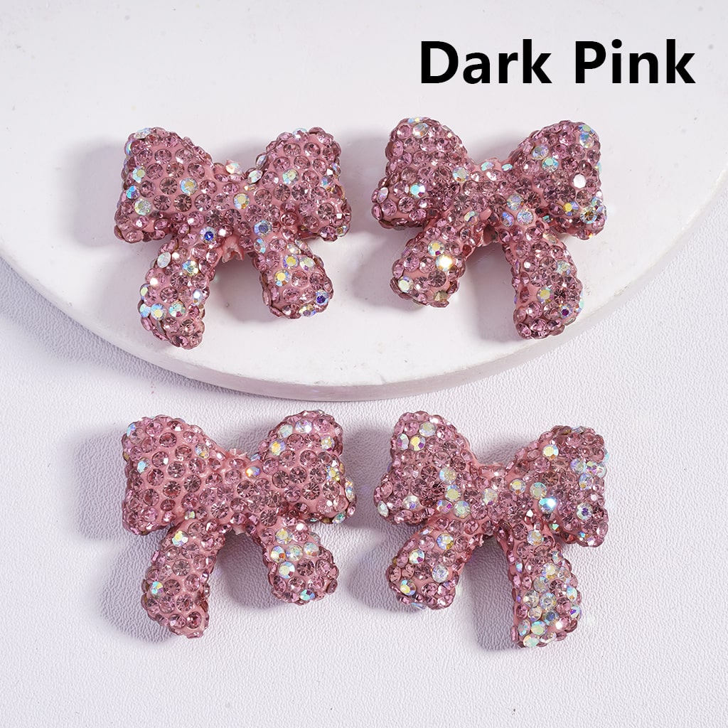 Dark pink bow-shaped hair clip with rhinestones on a white background

