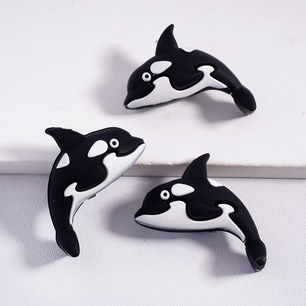 Three black and white whale-shaped objects on a light gray background