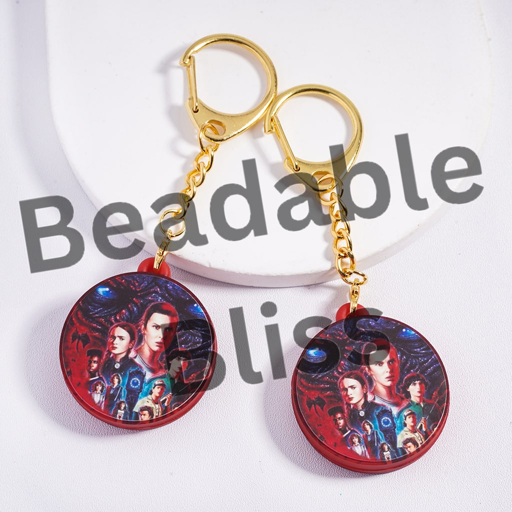 Keychain with circular charms featuring a group of people on a red background, branded 'handsonsupply.com'.