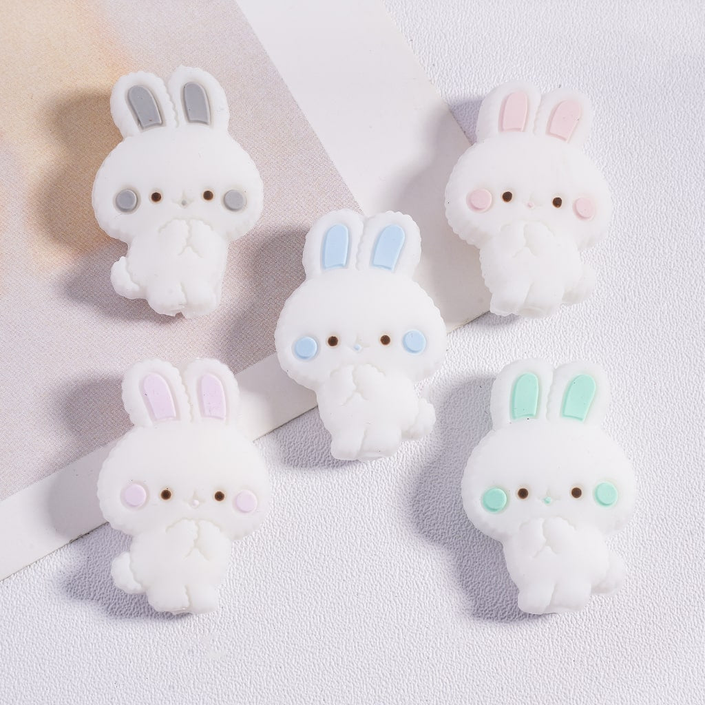 Five cute cartoon rabbit figurines with different colored ears on a light background