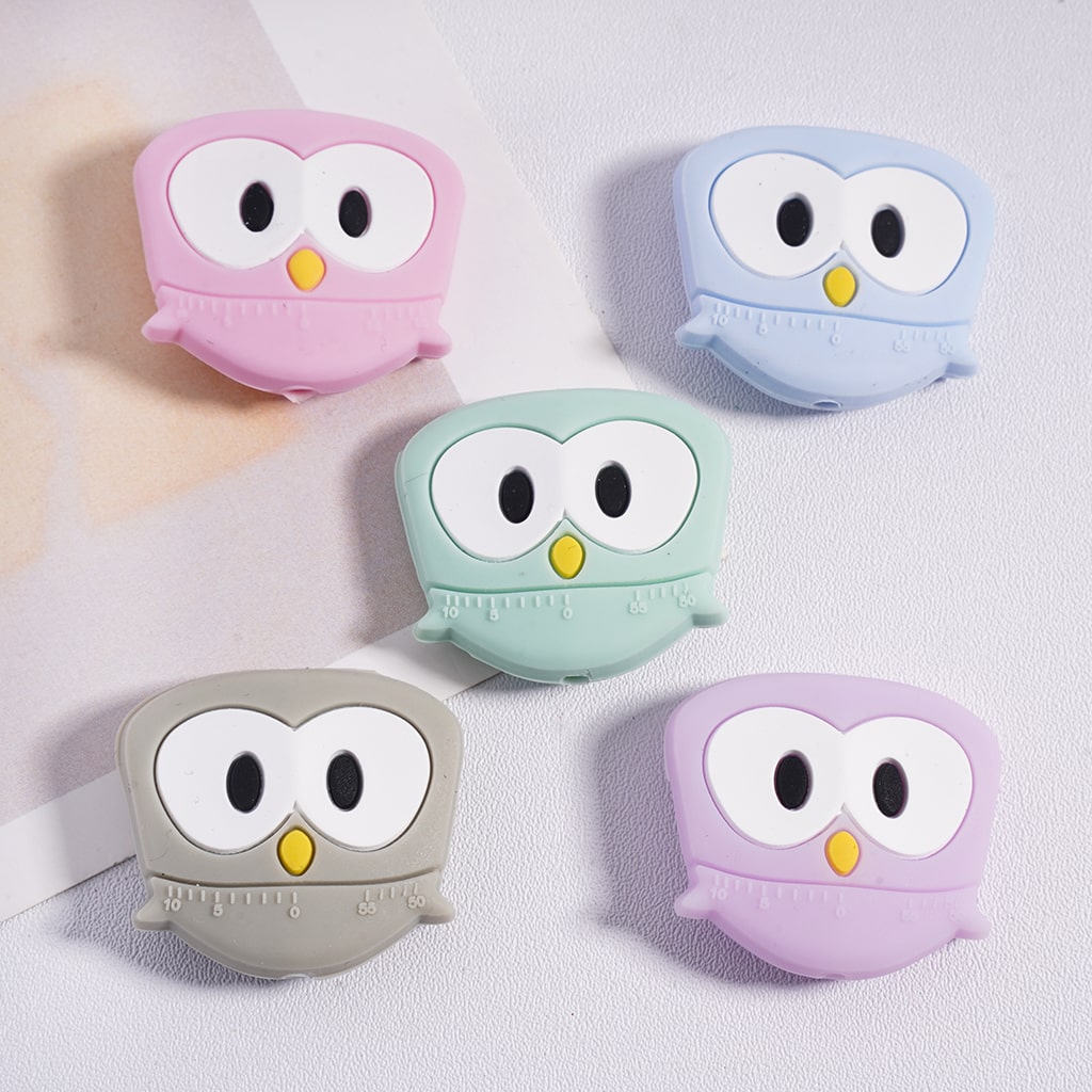 Five owl-shaped air pod cases in pink, blue, green, gray, and purple on a light background.