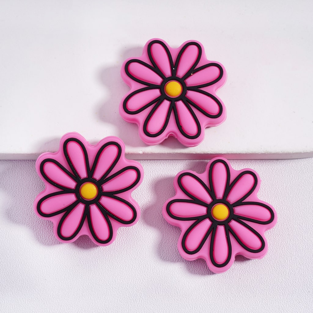 Three pink flower-shaped objects with black outlines and yellow centers on a white background