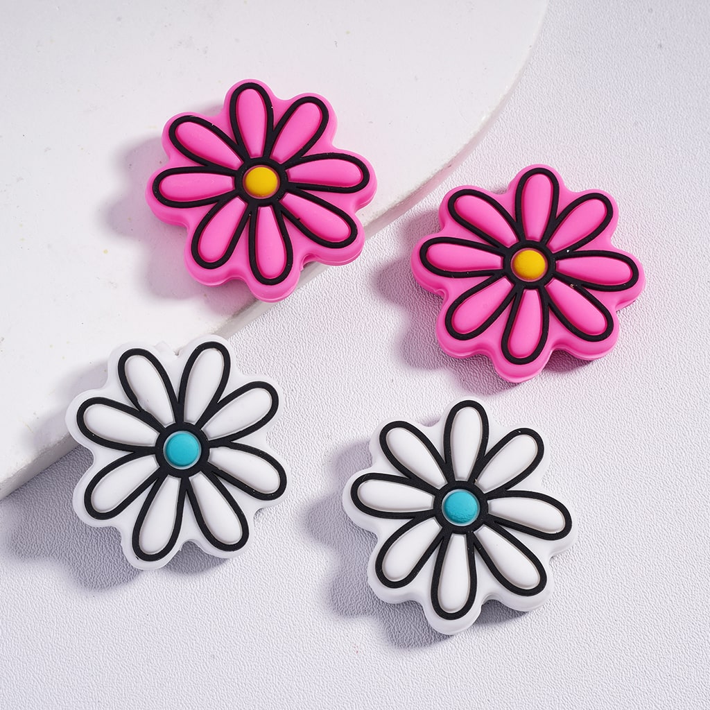 Two pairs of flower-shaped earrings on a light gray background