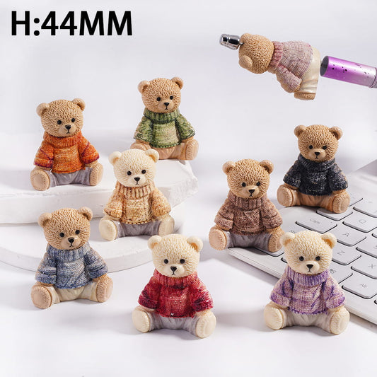 Small teddy bears wearing colorful sweaters on a white surface with a keyboard.