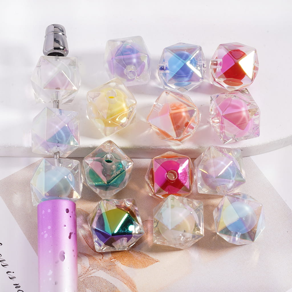 Colorful crystal-like objects on a white surface with a pen.

