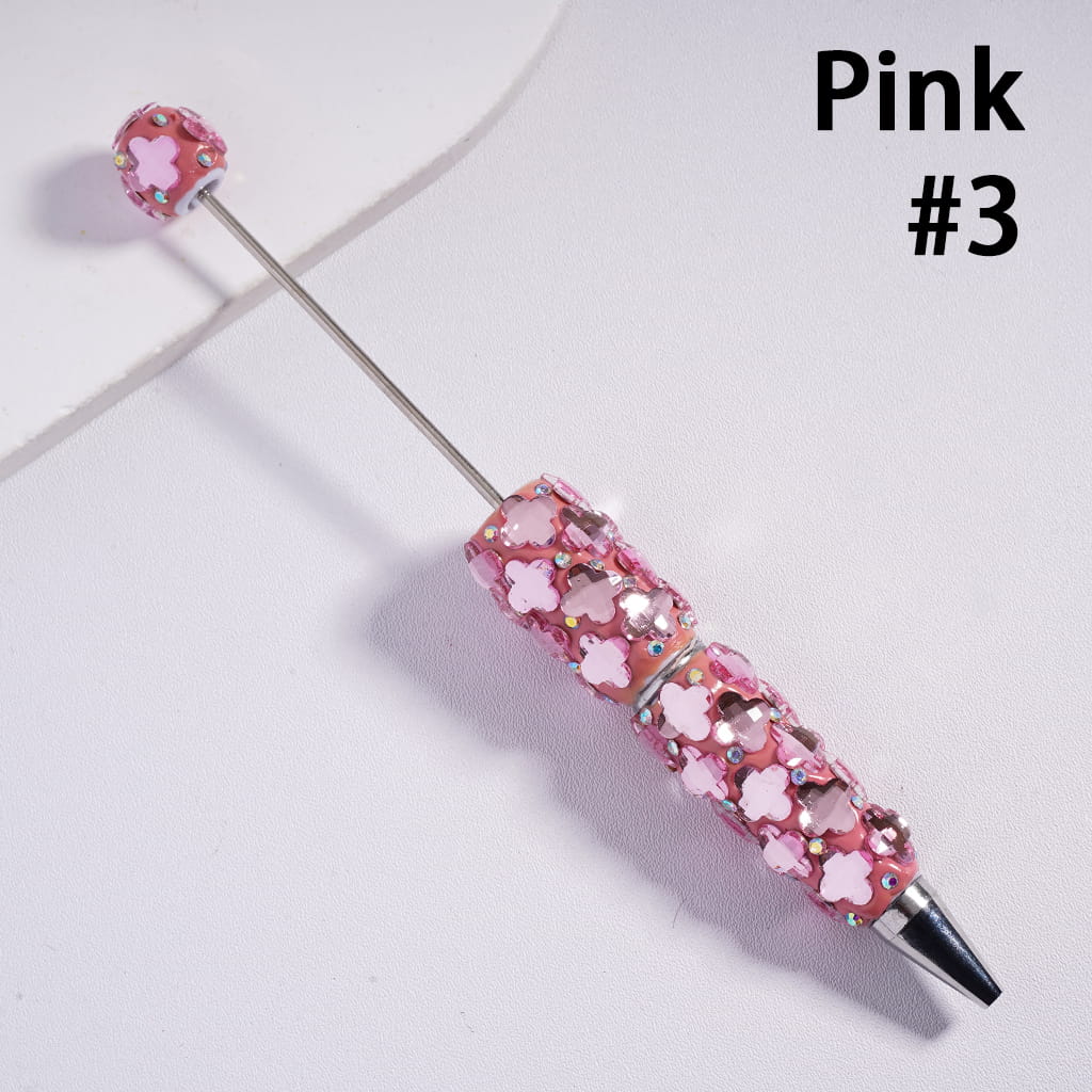 Pink beaded stick with floral designs on a light gray background