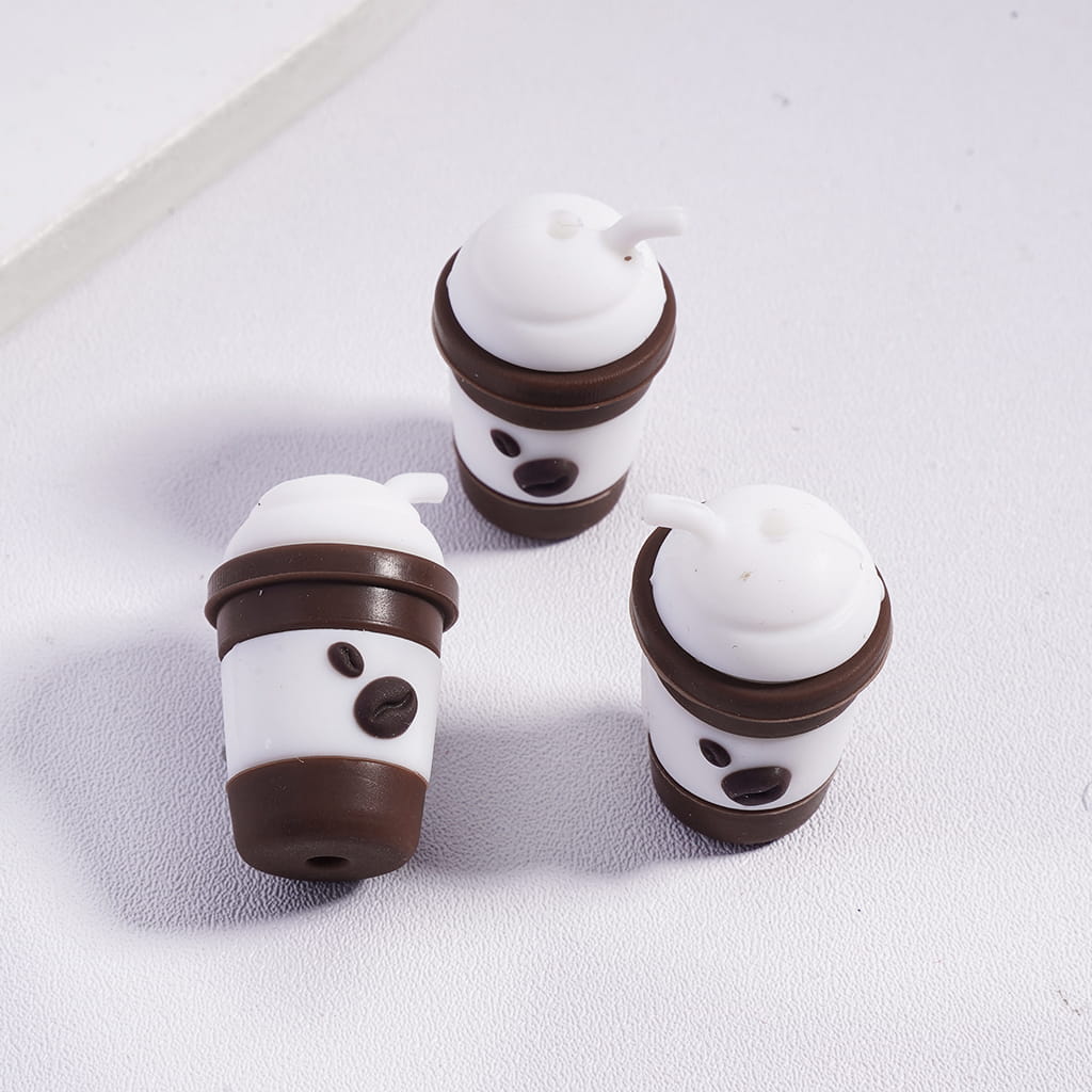 Three coffee cup-shaped objects with whipped cream and chocolate drizzle on a white surface

