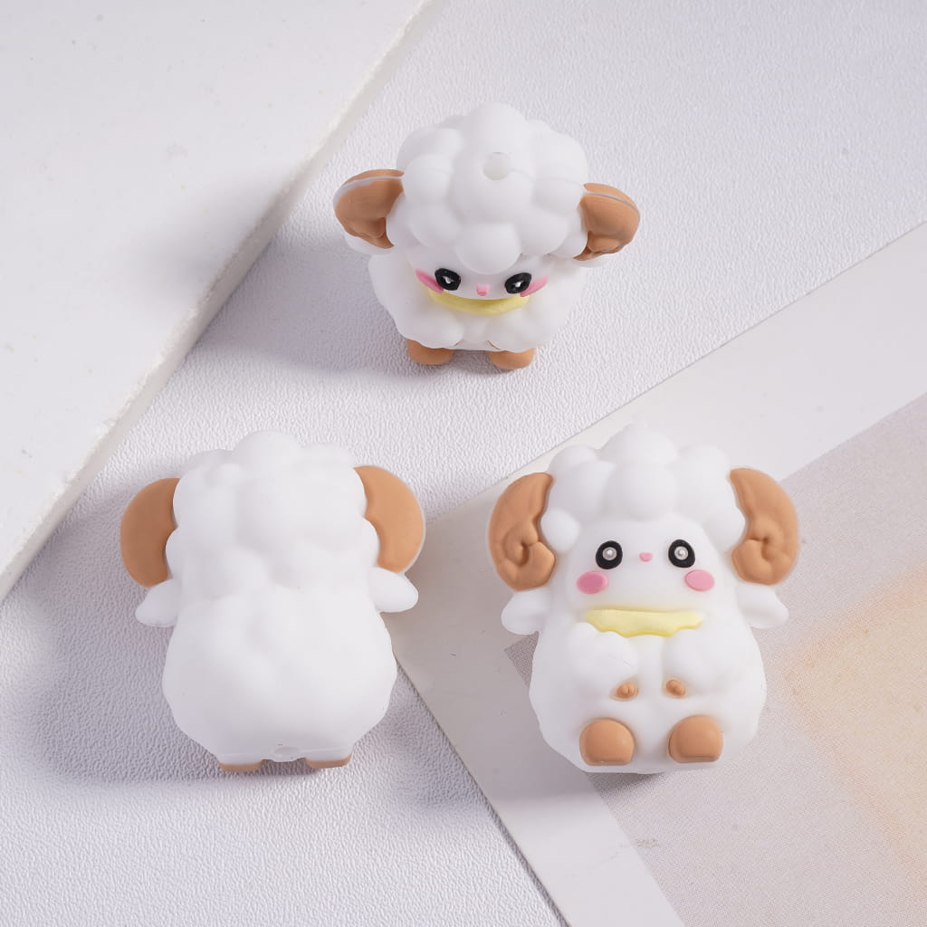 Three cute cartoon-style sheep figurines on a light surface