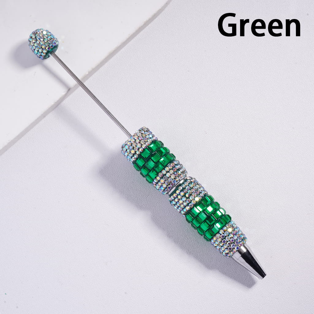 Decorative pen with green gemstones on a light gray background